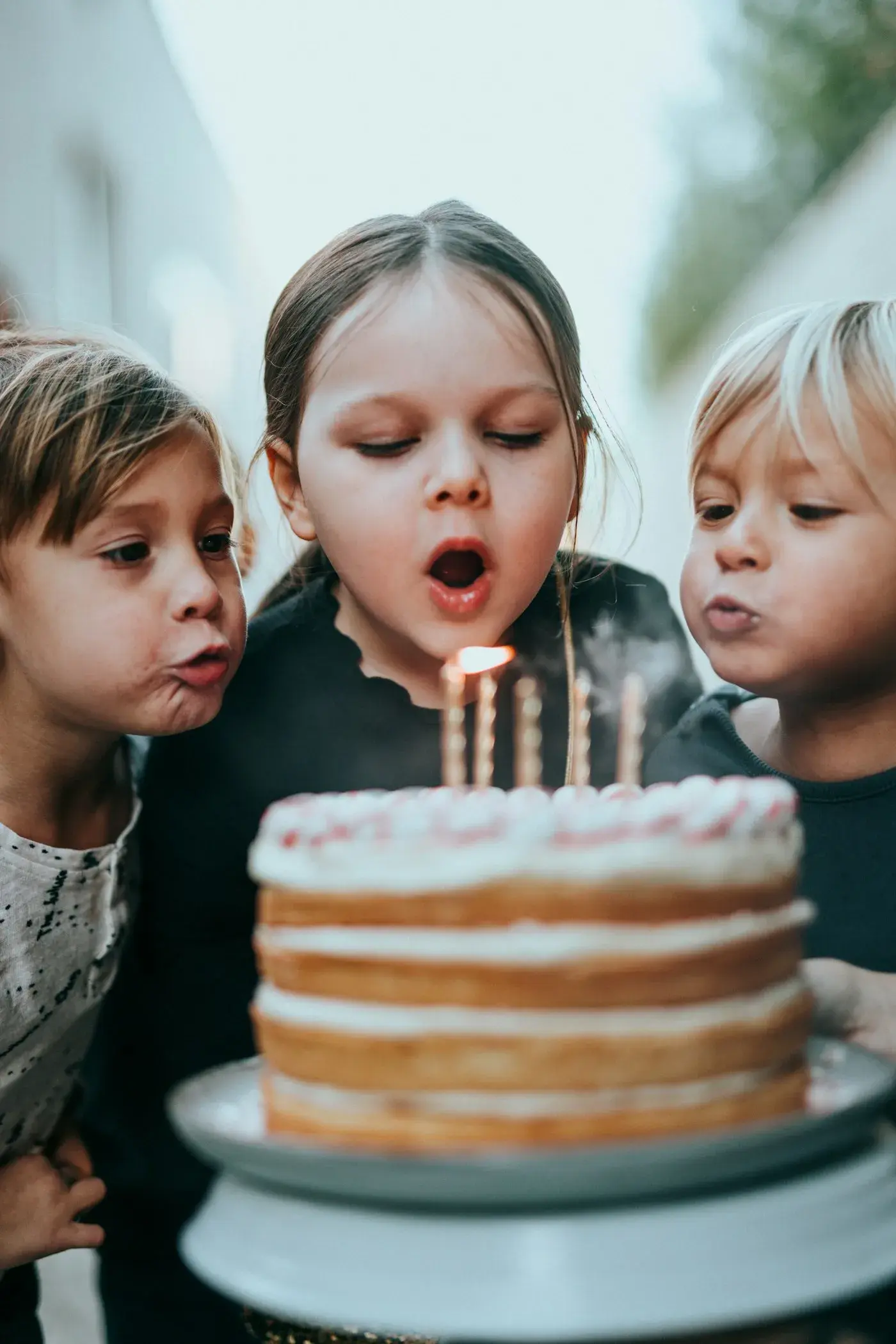 Tre bambini soffiano insieme le candeline della torta