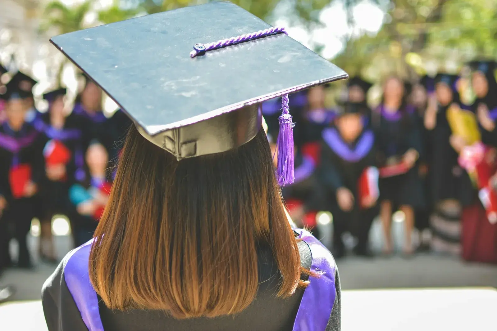 Una ragazza con il tocco di laurea davanti agli altri laureati